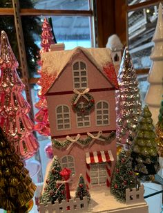 a pink doll house surrounded by christmas trees