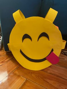 a yellow paper bag with a smiley face sticking out of it's mouth on the floor