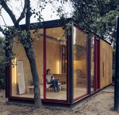 a woman sitting on a bench in front of a glass building with trees around it