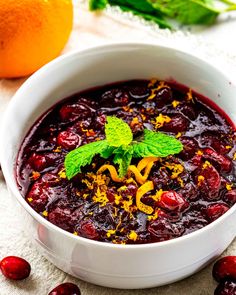 a white bowl filled with cranberry sauce and garnished with fresh mint