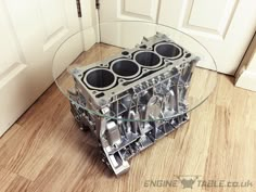 an engine block is sitting on the floor next to a glass table with spoons in it