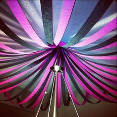 a pink, blue and white striped tent with lights on it's sides hanging from the ceiling