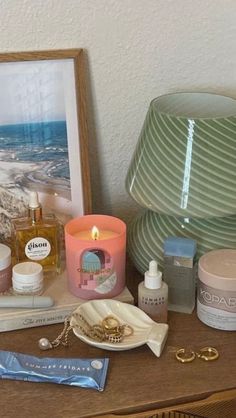 an assortment of personal care items on a table next to a framed photograph and candle