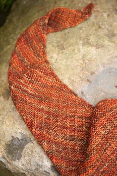 an orange knitted necktie sitting on top of a rock