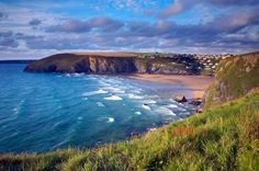 the beach is surrounded by green grass and blue water