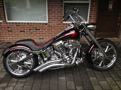 a red and black motorcycle parked in front of a brick building