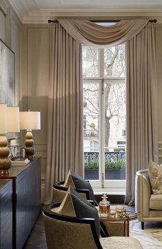 a living room filled with furniture and a large window covered in beige draping