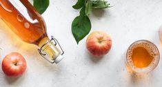 apple cider, apples and leaves on a white surface with green leaves around it