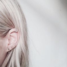 a woman with blonde hair wearing a pair of ear piercings on her left side