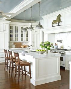 a large kitchen with white cabinets and wooden flooring, along with an island in the middle