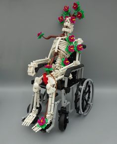 a skeleton sitting in a wheel chair with flowers on it's head and arms