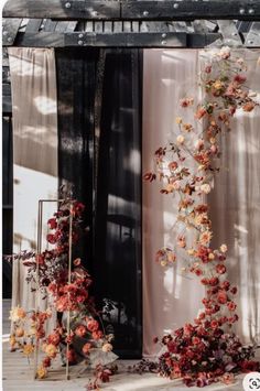 an arrangement of flowers on display in front of a window with sheer drapes and curtains