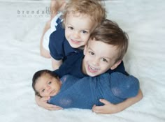 three children laying on the bed with their arms around each other and smiling at the camera