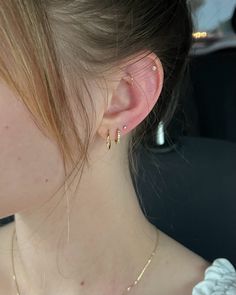 a close up of a person wearing some kind of earring with gold chains on it