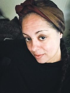 a woman with braids and a bandana on her head looking at the camera