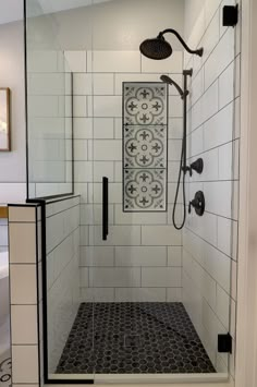 a shower with black and white tile on the floor