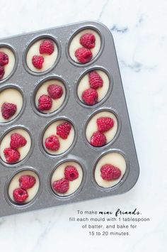 raspberries are placed in muffin tins on a marble counter top, ready to be baked