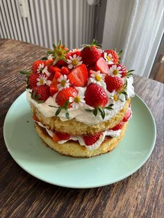 a strawberry shortcake with whipped cream and fresh strawberries on top is sitting on a green plate