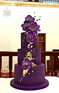 a three tiered purple cake with flowers on it