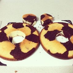 two chocolate covered donuts sitting on top of a white plate next to each other