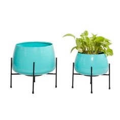 two blue planters with plants in them sitting on black metal stands against a white background