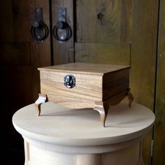 a small wooden box sitting on top of a white table next to some wood doors