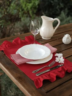 the table is set with red napkins and white plates, silverware and wine glasses