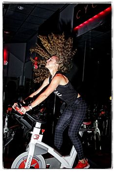 a woman riding a stationary bike with her hair blowing in the wind on display at a gym