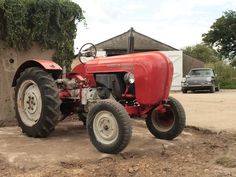 an old red tractor parked in front of a building