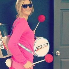 a woman in pink is holding a drum and some candy canes while standing next to a door