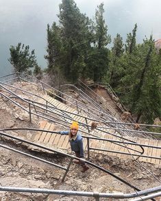 a man standing on top of a wooden ramp next to trees and stairs with metal railings