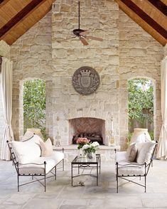 an outdoor living room with stone fireplace and furniture