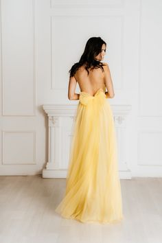 a woman in a yellow dress is standing against a wall with her back to the camera