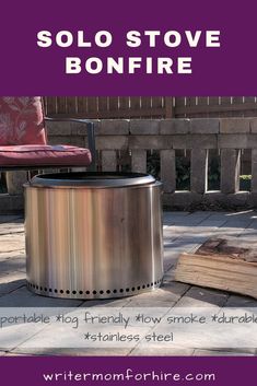 a metal fire pit sitting on top of a patio next to a purple chair and red pillow