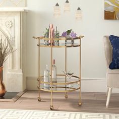 a gold bar cart with bottles and glasses on it in front of a fire place