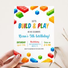 a hand holding up a lego birthday party card that says, let's build and play as we celebrate