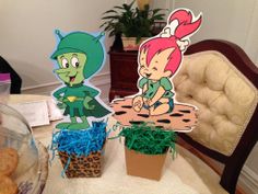 there are two plants and some paper cutouts on the table with cookies in front of them