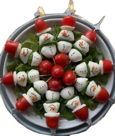 a white plate topped with tomato and mozzarella snowmen on skewers