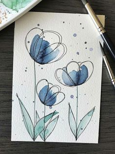 a watercolor painting of blue flowers on white paper next to some paintbrushes