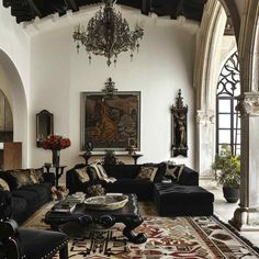 an ornate living room with black couches and chandelier