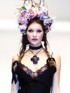 a woman with flowers in her hair wearing a black dress and choker on the catwalk