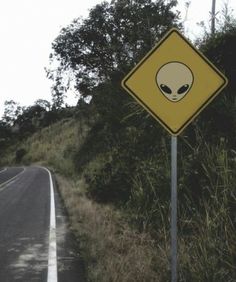 an alien warning sign on the side of a road