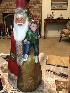 a little boy sitting on top of a santa clause figurine