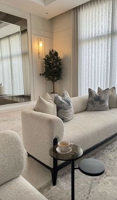 a living room filled with furniture and a large mirror on the wall above it's windows