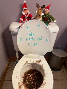 two elfs sitting on top of a toilet with cocoa in the bowl next to it