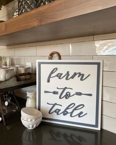 a sign that says farm to table sitting on a kitchen counter next to bowls and cups