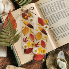 an open book sitting on top of a wooden table next to a candle and flowers