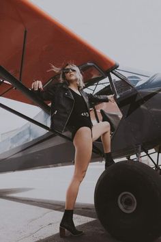 a woman leaning on the wing of an airplane