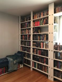 a room filled with lots of books on top of shelves next to a blue couch