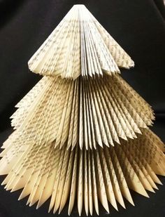 an origami christmas tree made out of book pages is displayed on a black background